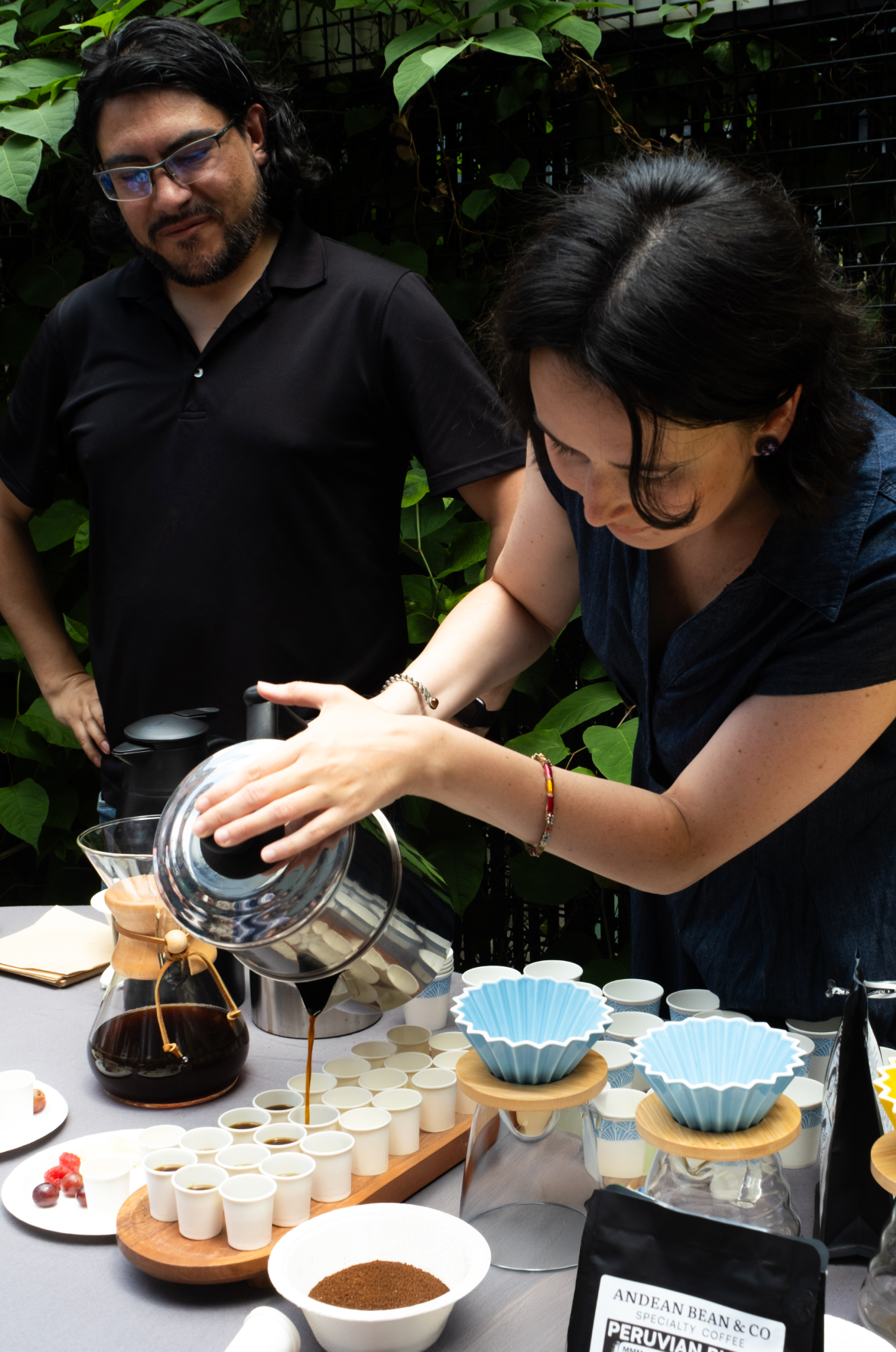 Woman pouring water into a Chemex and serving Café Pasado during a specialty coffee brewing demo at an outdoor tasting in New York