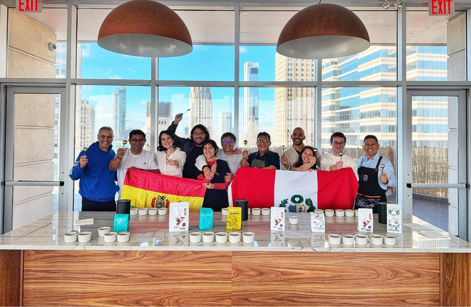 Group of coffee professionals and guests holding Peruvian and Bolivian flags during a cupping event in New York City, celebrating Latin American coffee