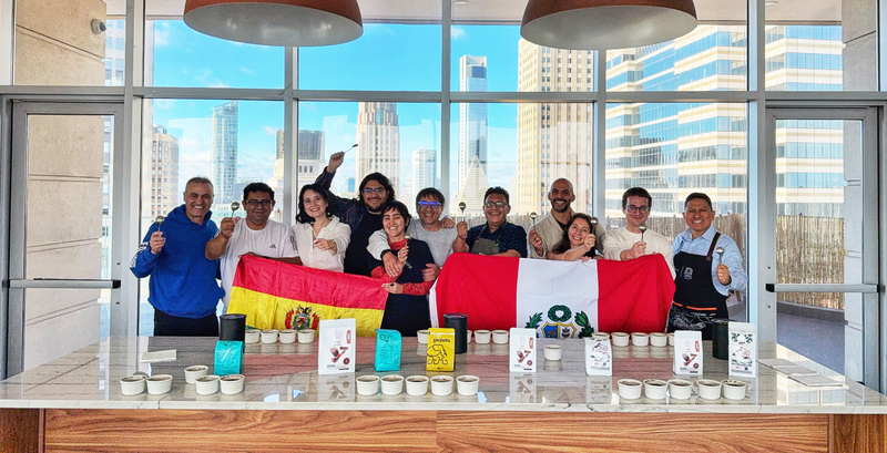 Group of coffee professionals and guests holding Peruvian and Bolivian flags during a cupping event in New York City, celebrating Latin American coffee